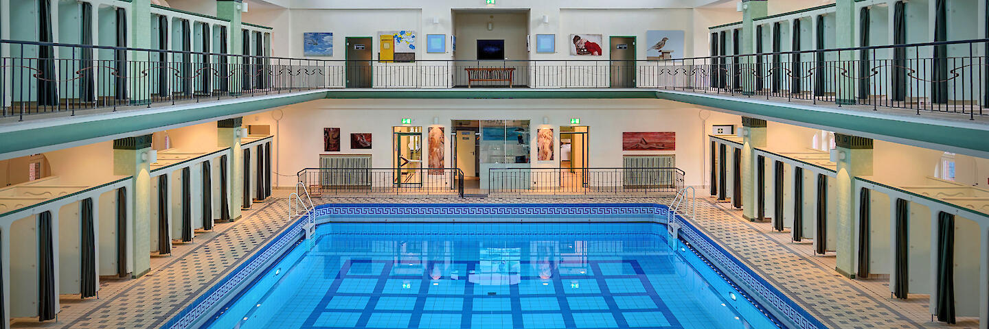 Schwimmhalle mit basilikale Gewölbe. Mehrzweckbecken sowie die Umkleiden, die auf zwei Etagen um das Becken herum verteilt sind.