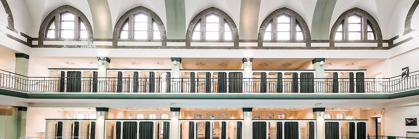 Schwimmhalle mit basilikale Gewölbe. Mehrzweckbecken sowie die Umkleiden, die auf zwei Etagen um das Becken herum verteilt sind.