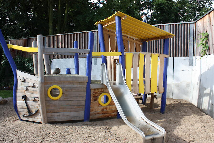 Kinderspielplatz mit einem Kletterboot mit Rutsche.