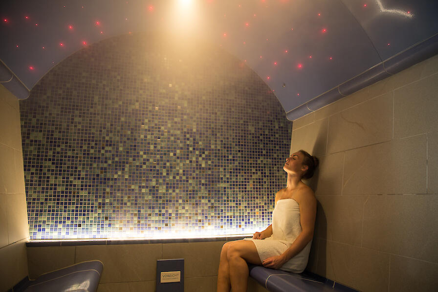 Dampfbad Höyry mit einer blauen Wand und Decke und einer Frau die entspannt.