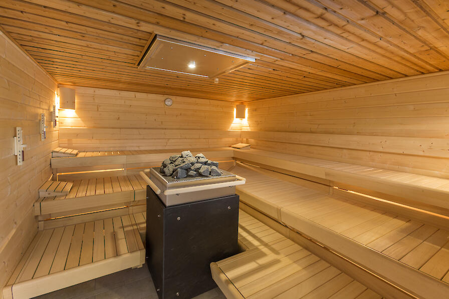 Dünen-Sauna mit einem Saunaofen in der Mitte der Sauna.