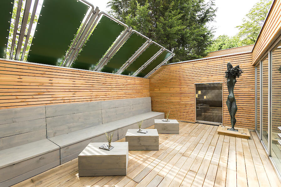 Außenterrasse mit Sitzbänken und Tischen aus aus Stein.