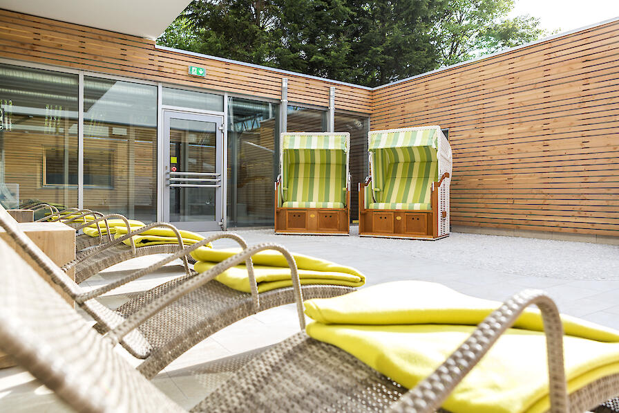 Außenterrasse mit zwei Strandkörben und mehreren Liegen.