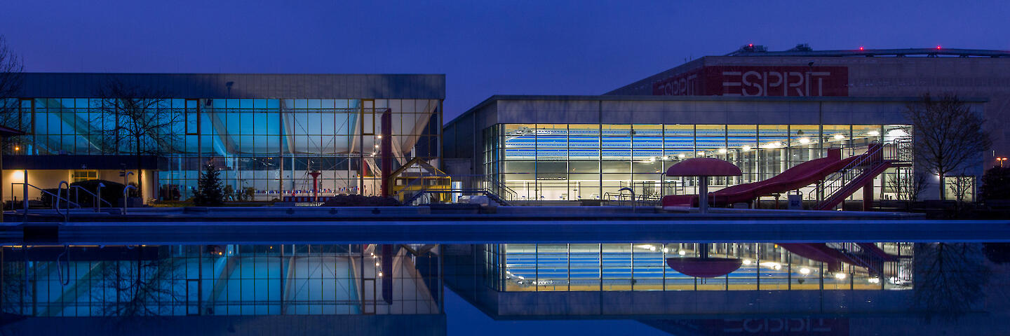 Außenansicht bei Nacht von der 33m-Halle, der 50m-Halle und dem Freibad.
