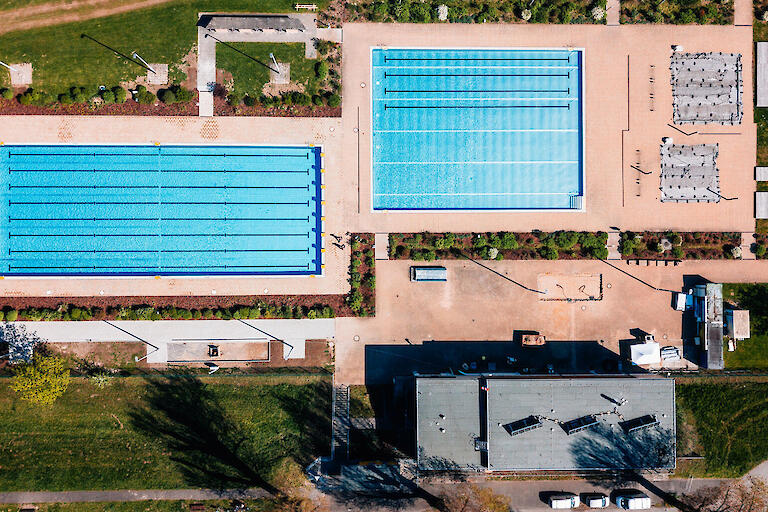 Luftansicht des Strandbades Lörick mit dem 50m-Schwimmerbecken, dem Mehrzweckbecken, zwei Planschbecken und einem Kassenhäuschen.