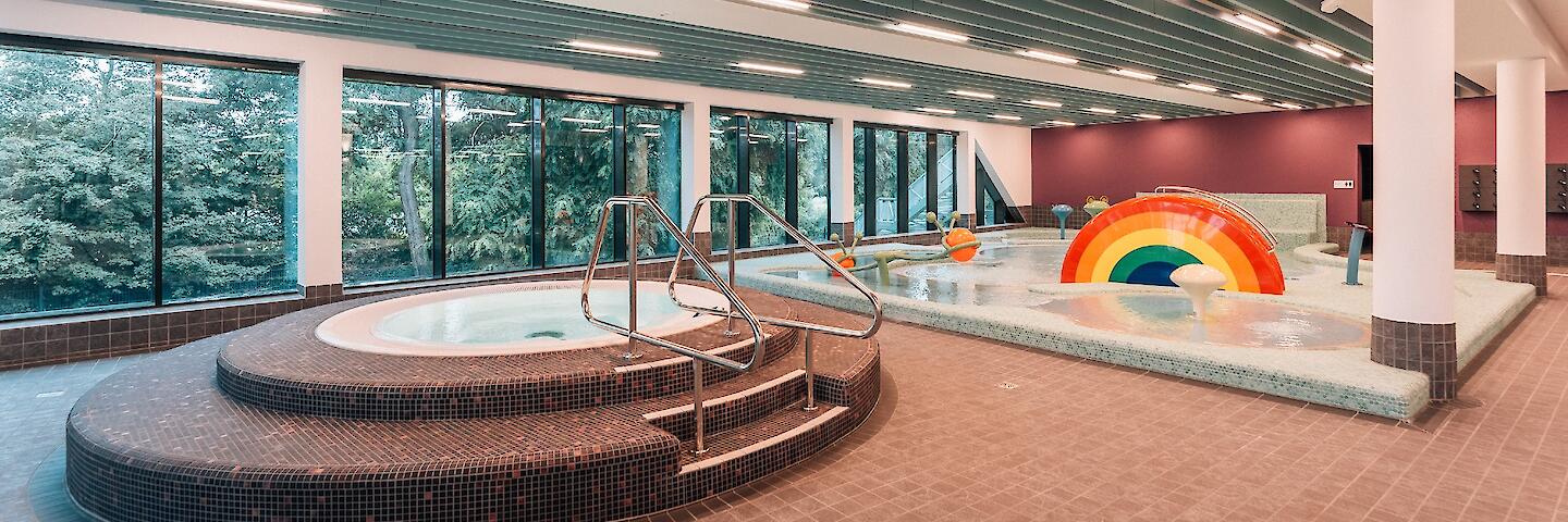 Kinderplanschbecken mit verschiedenen Attraktionen für Kinder sowie einem runden Warmwasserbecken.