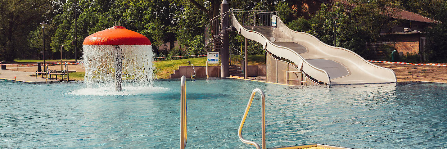 Mehrzweckbecken mit verschiedenen Attraktionen wie ein Wasserpilz und einer Breitrutsche.