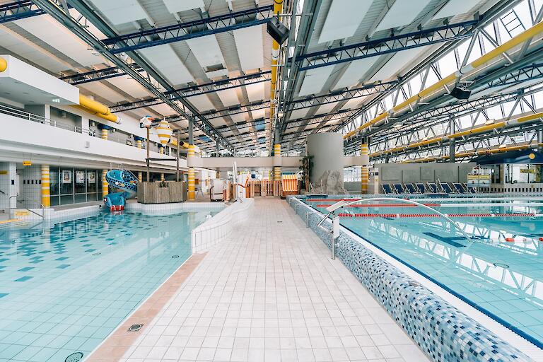 Schwimmhalle im Freizeitbad Düsselstrand. Übungsbecken mit Wasserballtor, Wasser-Basketballkorb und Kinder-Schlangenrutsche sowie ein Ende des 25m-Beckens.