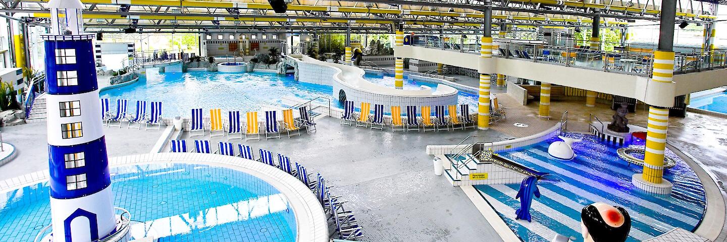 Schwimmhalle im Freizeitbad Düsselstrand. Das Bewegungsbecken hat einen Leuchtturm in der Beckenmitte, das Spiel- und Tummelbecken mit einer Reifenrutsche sowie das Kleinkind-Planschbecken mit einer kleinen Rutsche.