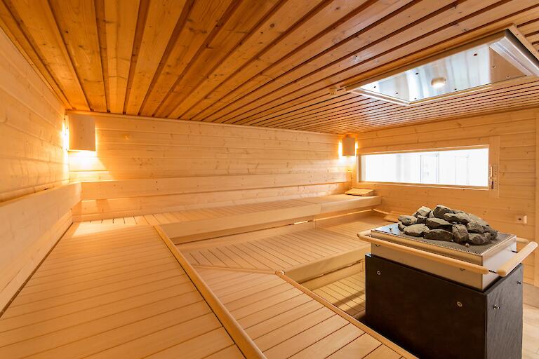 Dünen-Sauna mit einem Saunaofen in der Mitte der Sauna.