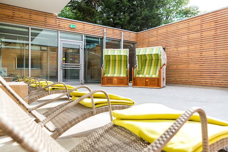 Außenterrasse mit zwei Strandkörben und mehreren Liegen.