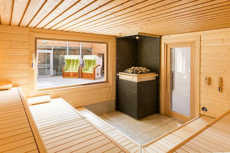 Gezeiten-Sauna mit einem Aufgussofen und einem Fenster nach draußen.