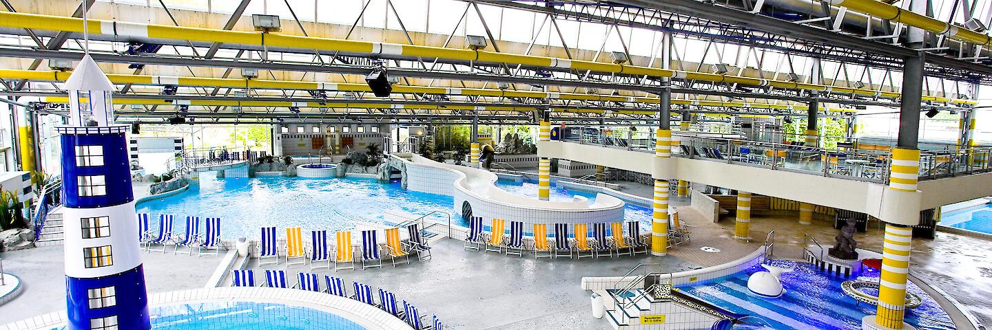 Schwimmhalle im Freizeitbad Düsselstrand. Das Bewegungsbecken hat einen Leuchtturm in der Beckenmitte, das Spiel- und Tummelbecken mit einer Reifenrutsche sowie das Kleinkind-Planschbecken mit einer kleinen Rutsche.