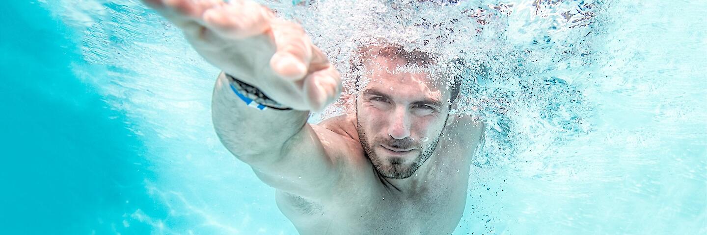 Unterwasseransicht von einem Mann der im Kraulstil schwimmt.